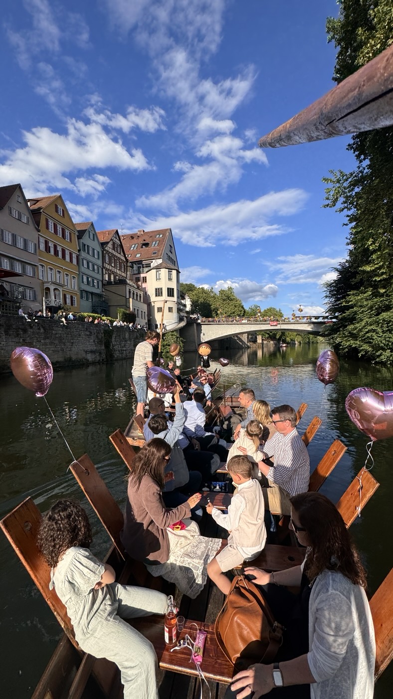 A celebration with heart balloons on the punt in front of Tübingen's colourful riverfront houses at golden hour